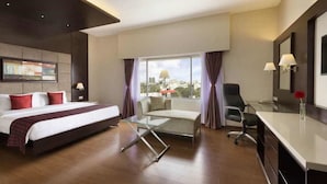 A modern hotel room with a bed, a glass table, a sofa, and a desk.