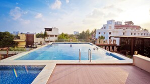 A rectangular swimming pool with metal railings, surrounded by a wooden deck.