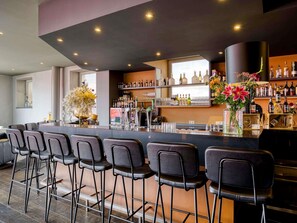 A bar area with a long counter, multiple stools, and a variety of bottles and glasses. - Mercure City Amersfoort Centre Hotel (Amersfoort)