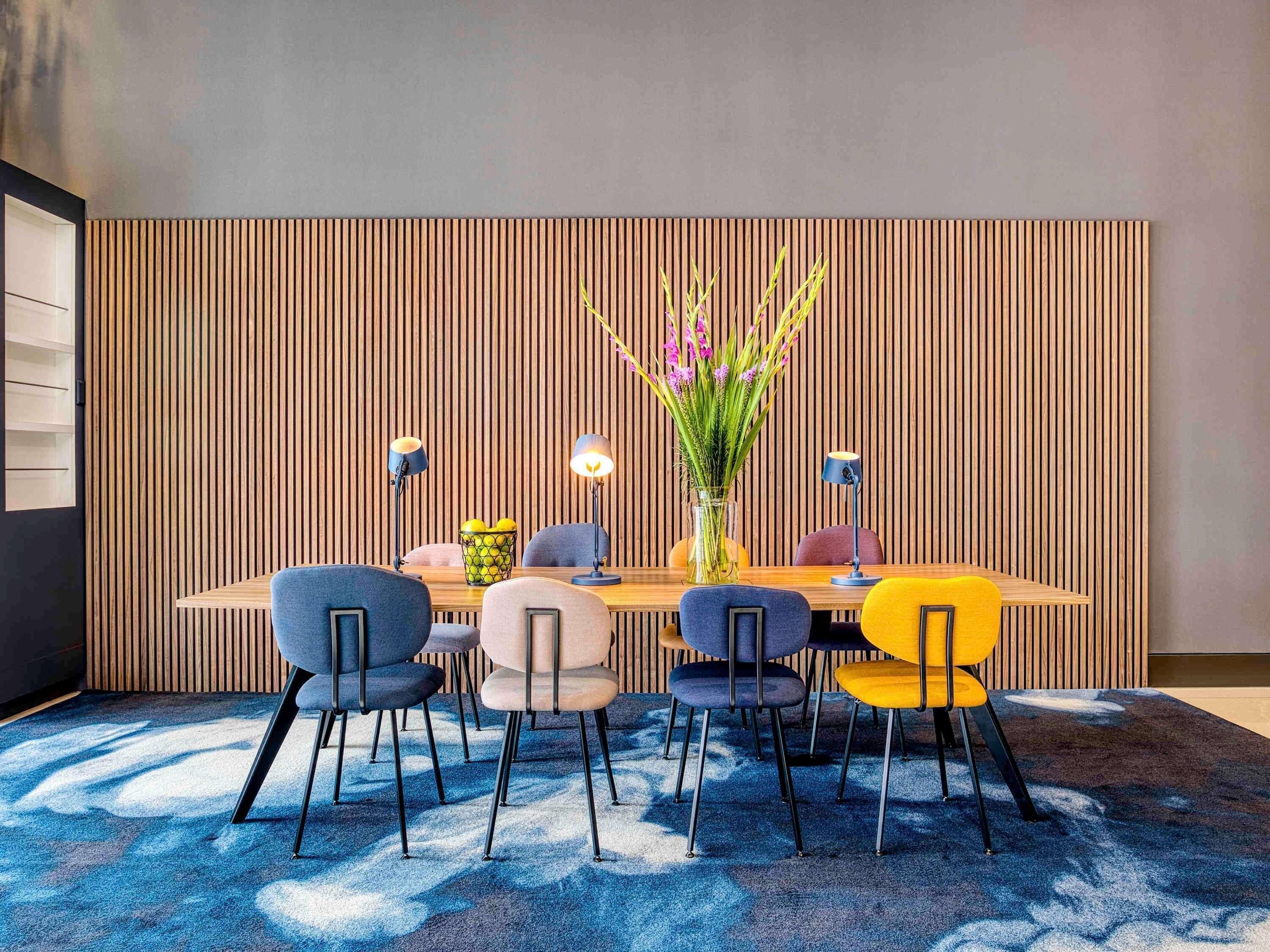 Een moderne eethoek met een wand van houten latten, een ronde tafel en zes stoelen met zwarte poten.