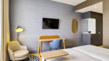 A modern hotel room with a bed, a desk, a chair, a TV, and a mirror.