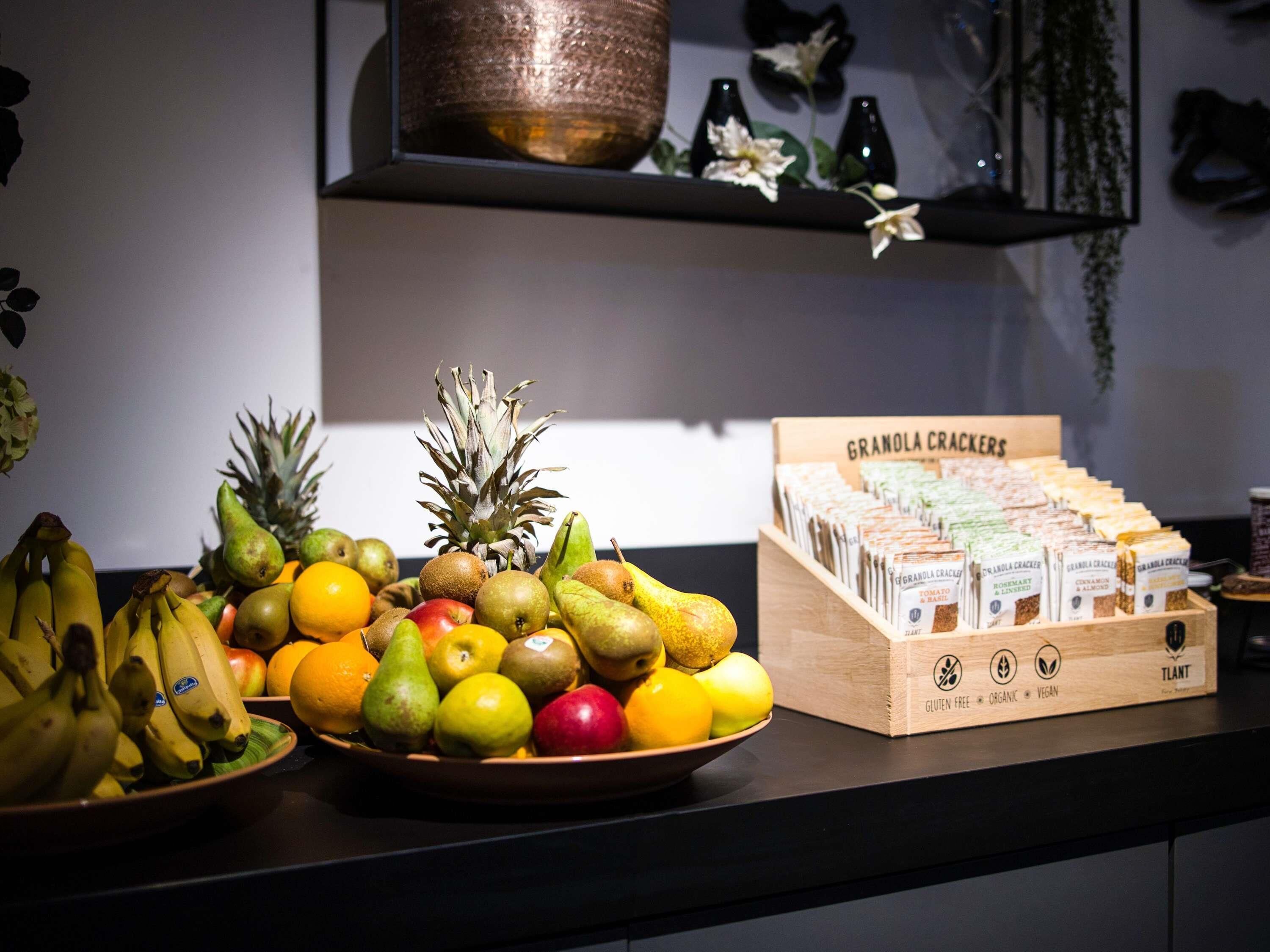 Un comptoir de cuisine avec une variété de fruits et une boîte de biscuits aux céréales.
