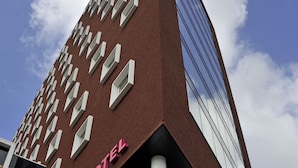 A tall hotel with a modern design, featuring a prominent 'Mercure Hotel' sign, large windows, and a clear sky in the background.