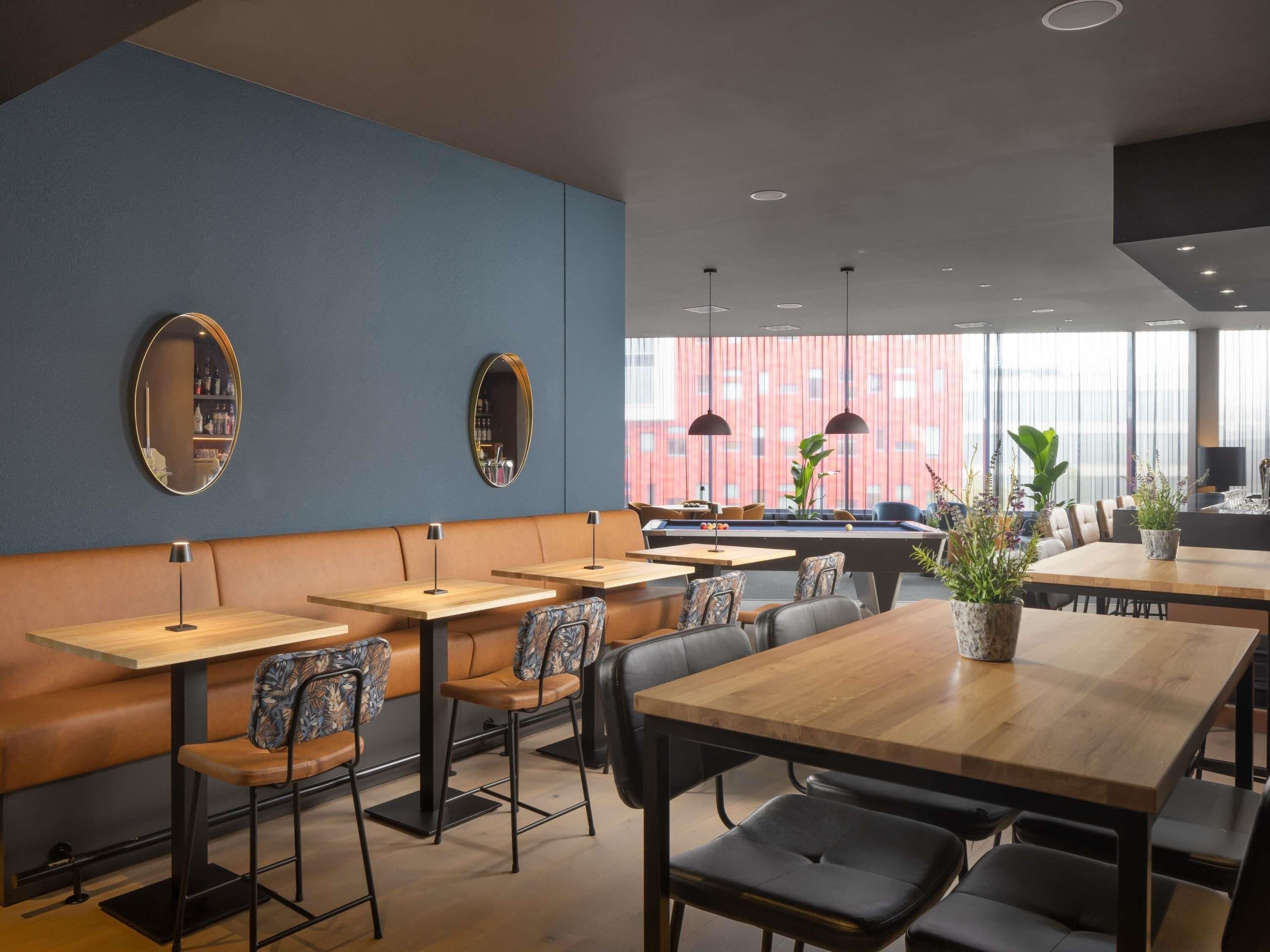 Un espacio interior moderno con arreglos de asientos, una mesa de billar y amplios ventanales.