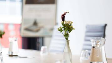Et bord med en vase blomster, glas og et kande.
