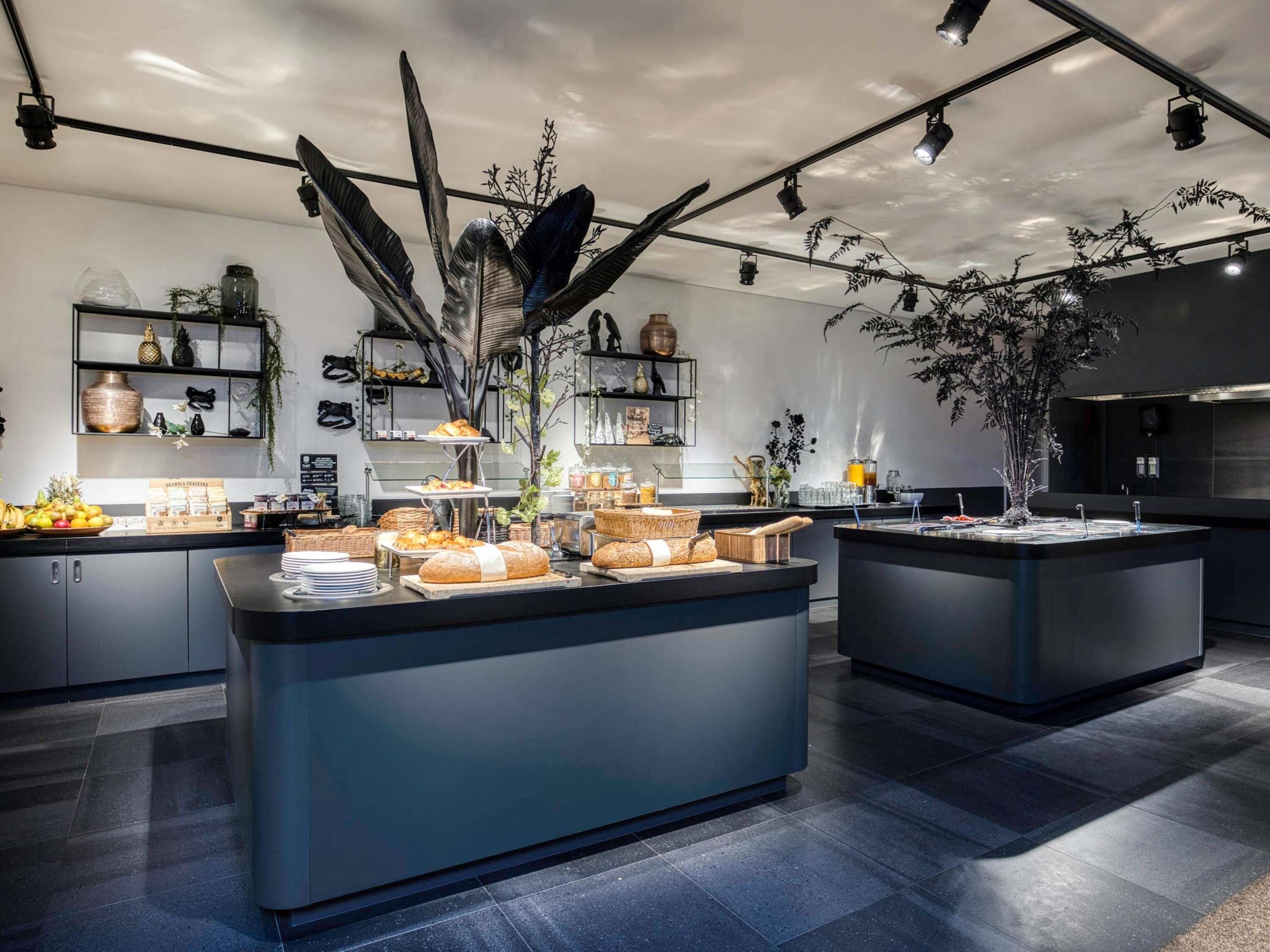 Een moderne keuken met een centraal eiland, zwarte aanrechtbladen en diverse etenswaren.