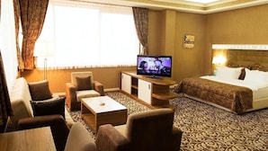 Una habitación de hotel con cama, televisión, sofá y mesa de centro.