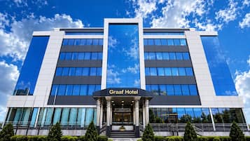 A modern hotel building with a prominent entrance, large windows, and a clear sky.