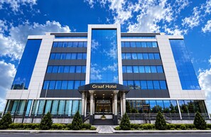 En modern hotellbyggnad med en framträdande entré, stora fönster och en klar himmel.