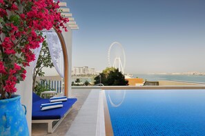 Una piscina al aire libre, sombrillas, sillones reclinables de piscina