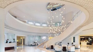 A spacious lobby with a central staircase, modern lighting, and a reception desk. - JA Ocean View Hotel, Jumeirah Beach Dubai (Dubai)