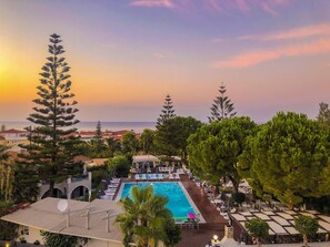 A resort with a swimming pool, lounge chairs, and a view of the sea at sunset. - Contessa (Zakynthos)