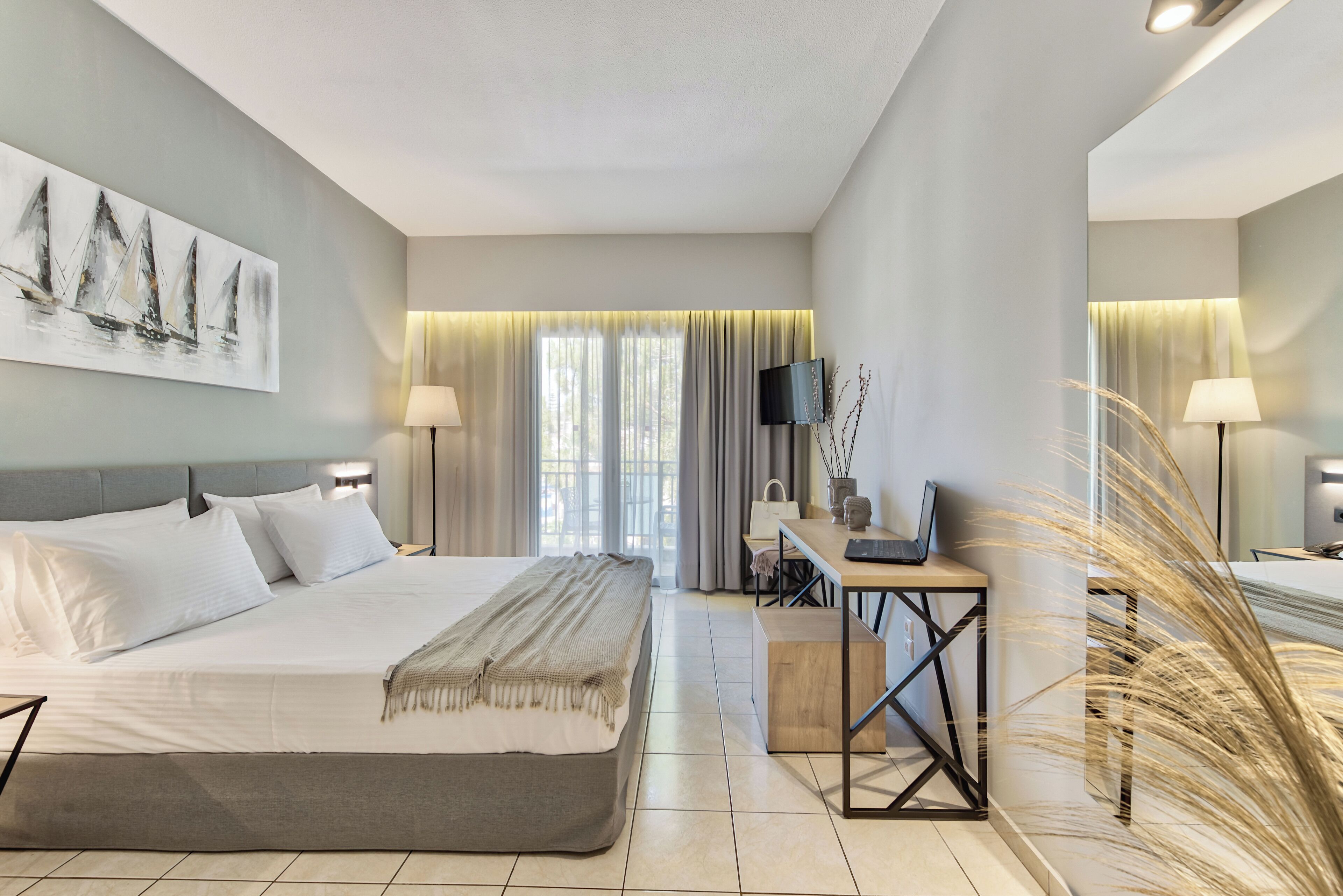 Une chambre d’hôtel moderne avec un grand lit, un bureau, une télévision et un tableau au mur.