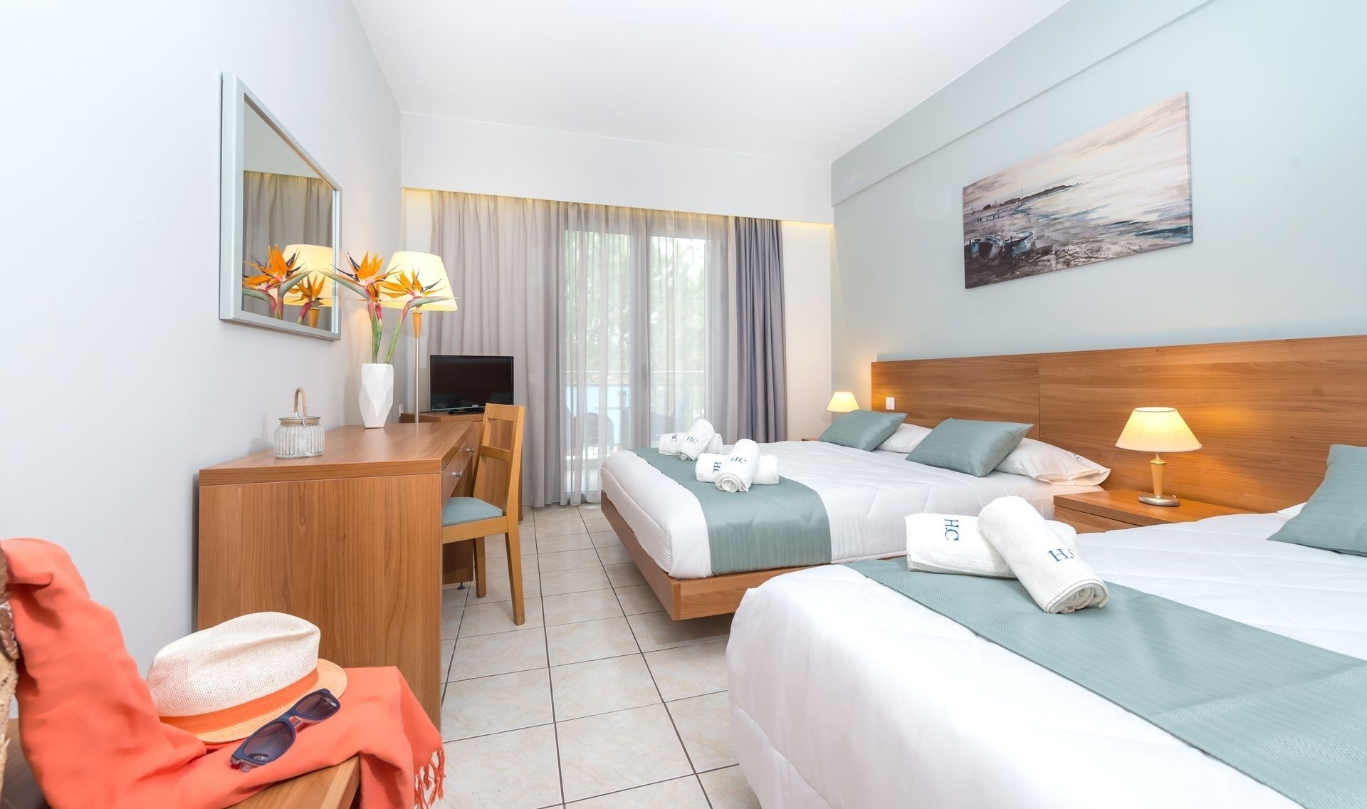 Une chambre d’hôtel avec deux lits, un bureau, une télévision et un tableau au mur.