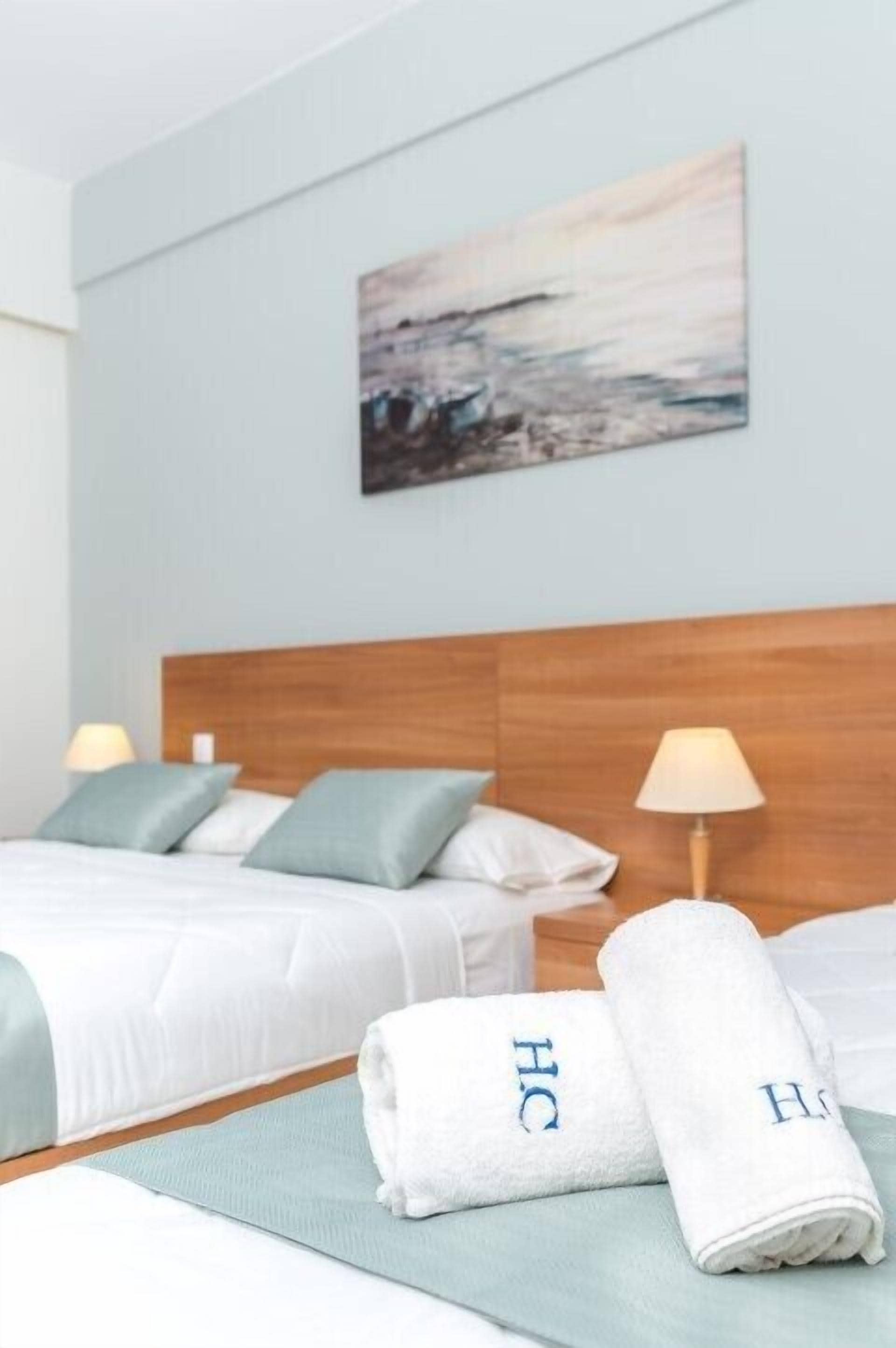 Una habitación de hotel con dos camas, cabecera de madera y un cuadro en la pared.