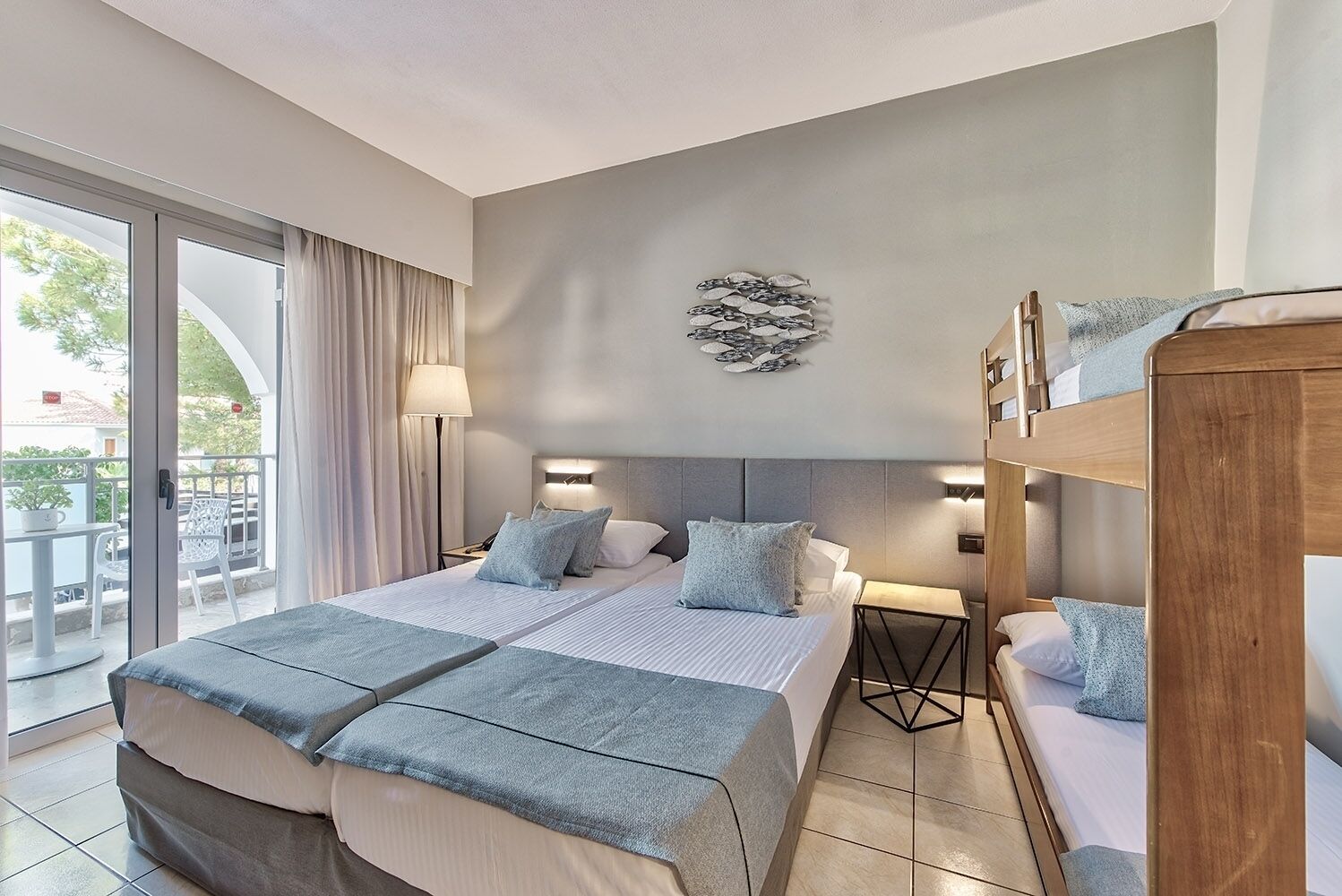 A modern hotel room with a large bed, a balcony, and a wooden bunk bed.