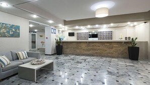 A modern lobby with a reception desk, a gray sofa, and a patterned floor.