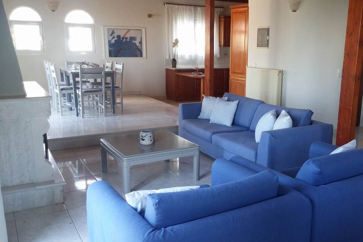 Una sala de estar con un sofá azul, una mesa de centro y un comedor con sillas y una mesa.