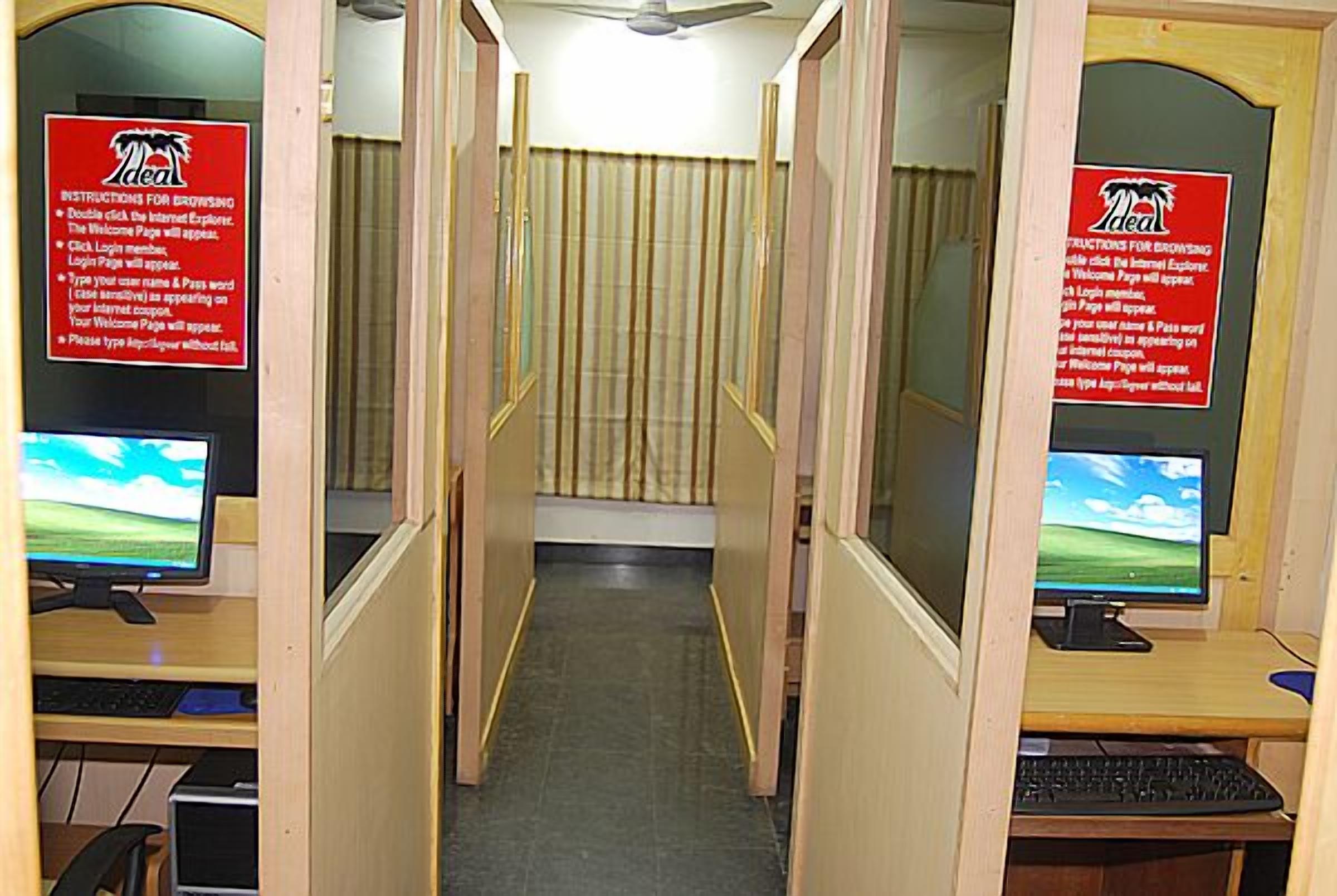 A row of cubicles with computers, each with a red sign providing instructions for using the internet.