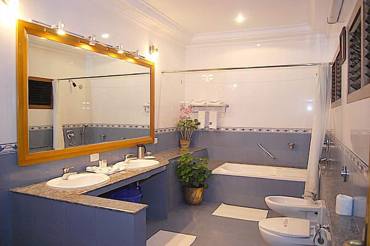 Un baño con dos lavamanos, una bañera y un inodoro.