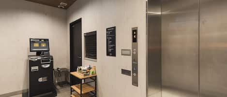 An elevator with a digital display, a vending machine, and a small table with items.