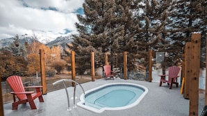 A swimming pool with wooden chairs and a view of mountains. - Lamphouse By Basecamp (Canmore)