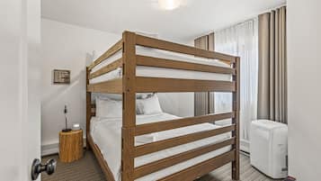 Una cama individual en un dormitorio de hotel, con una mesita de noche, una lámpara y un equipo de aire acondicionado.