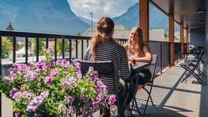 Two people sitting at an outdoor table with a mountain view. - Lamphouse By Basecamp (Canmore)