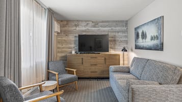 A modern living room with a flat-screen TV, grey sofas, and a wooden cabinet.