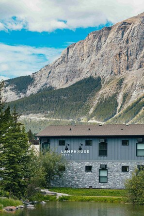 A hotel with a stone facade and multiple windows, set against a mountainous backdrop. - Lamphouse By Basecamp (Canmore)