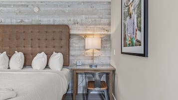 Una habitación de hotel con un cabecero capitonado, una mesita de noche con una lámpara y un cuadro enmarcado en la pared.