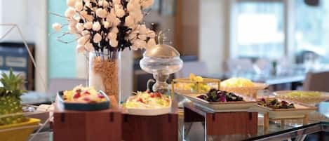 Una mesa de buffet con diferentes alimentos y un centro de mesa decorativo.