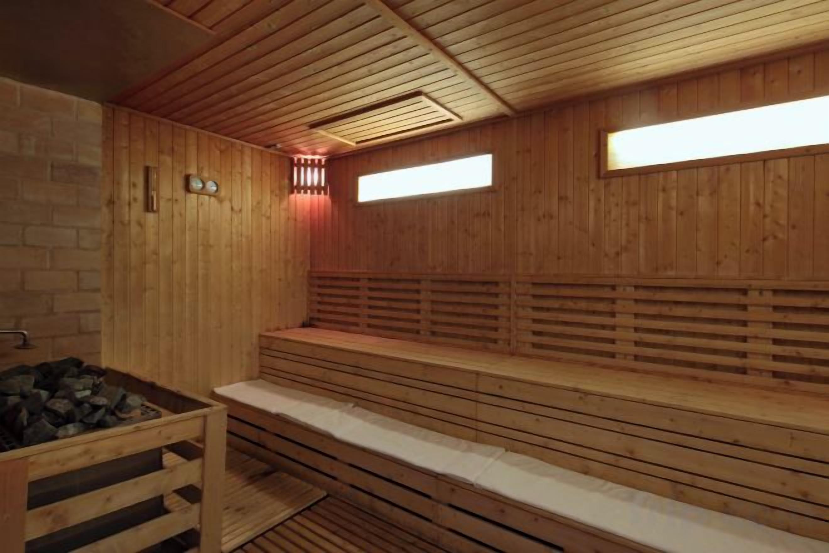Una sauna de madera con bancos y una pared de ladrillo.
