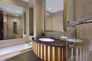 A modern bathroom with a large mirror, two sinks, a bathtub, and a glass shower enclosure.