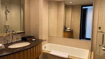 Un baño moderno con lavamanos, espejo y bañera.