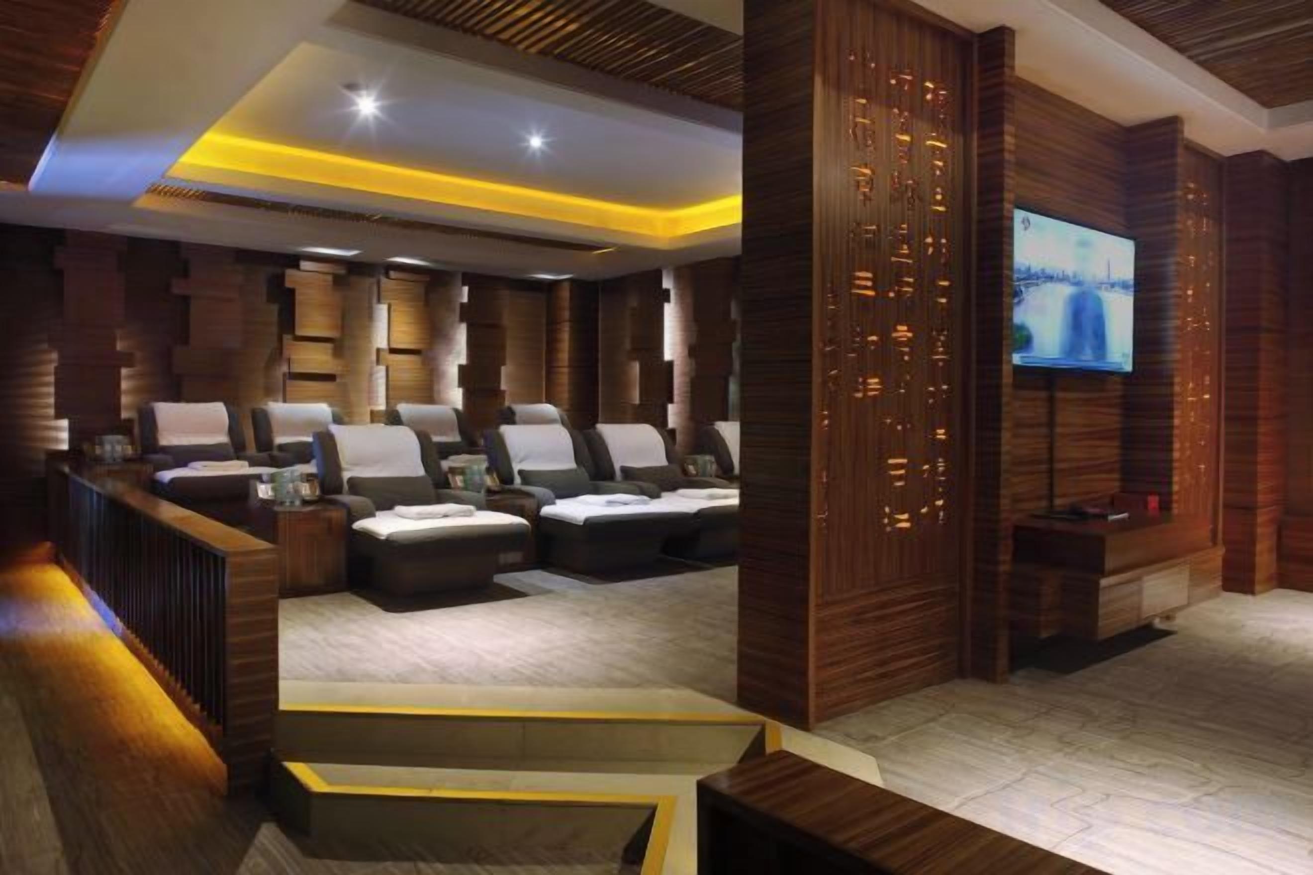 Un área de spa con varias sillas de masaje, un mostrador de recepción y una pantalla de televisión.