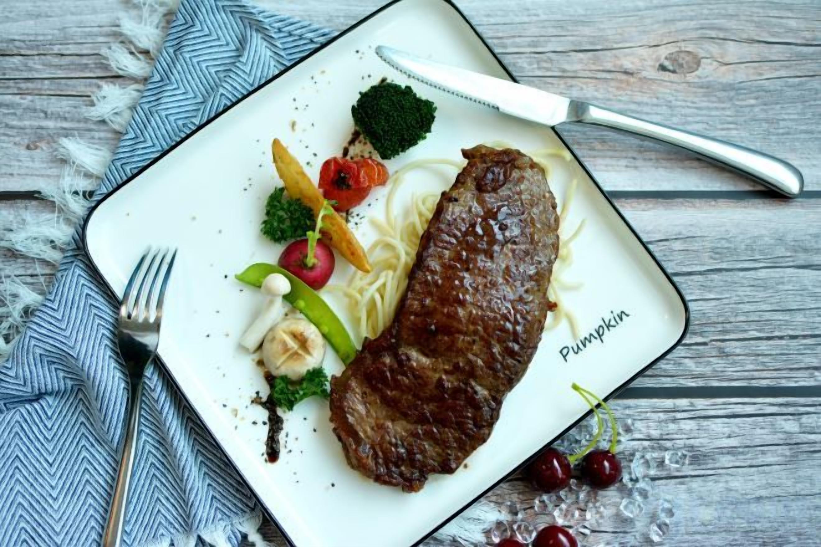 En tallerken med steak, grøntsager og en græskarpynt.