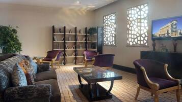 A hotel lobby with a sofa, chairs, a coffee table, and a bookshelf.