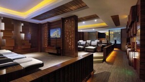 Uma área de spa moderna, com painéis de madeira, mesas de massagem e um balcão de atendimento.
