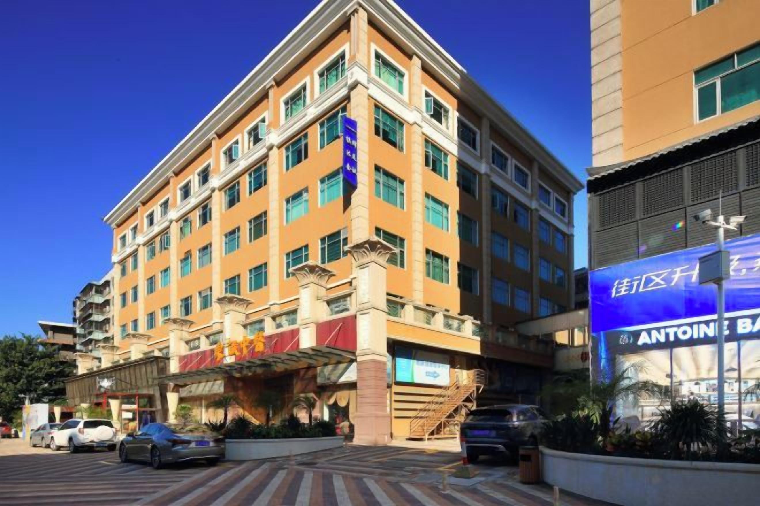 A multi-story hotel with a prominent entrance, a parking area, and a visible restaurant.