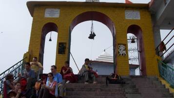 A temple entrance with steps leading up to a structure featuring a bell tower and a statue.