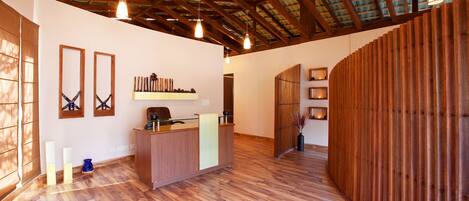 A spacious room with a wooden reception desk, a high ceiling with exposed beams, and a wooden partition wall.