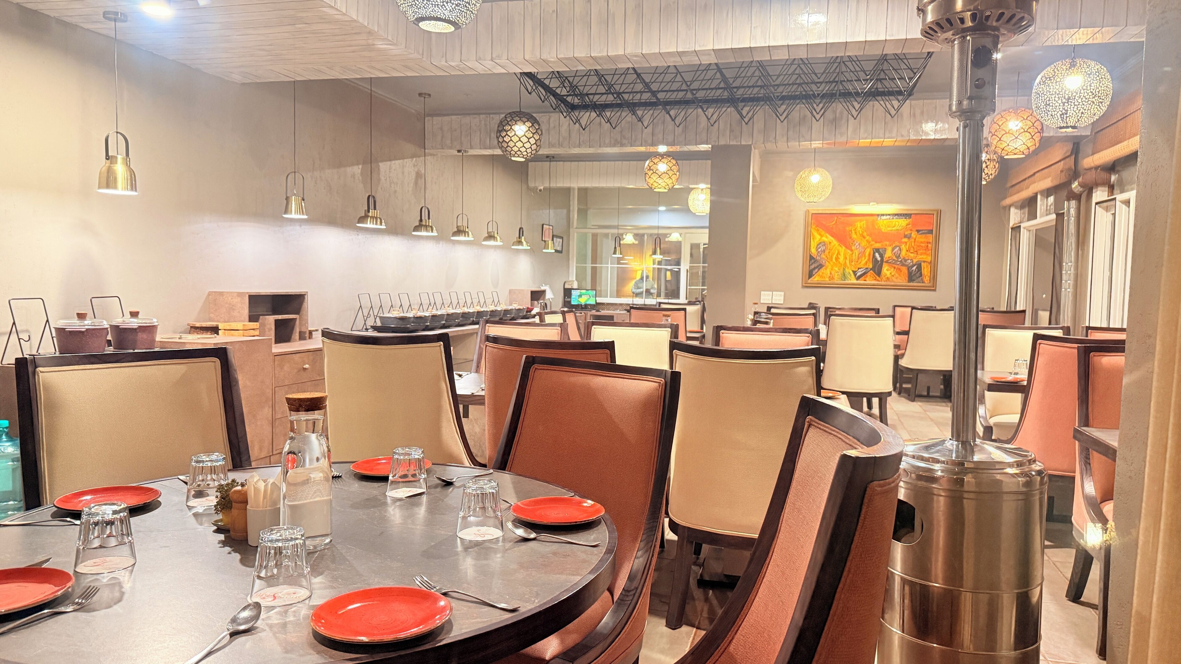 A restaurant with round tables, chairs, and hanging pendant lights.