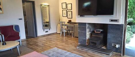 A modern living room with a fireplace, a television mounted above it, and a dining area with a table and chairs.