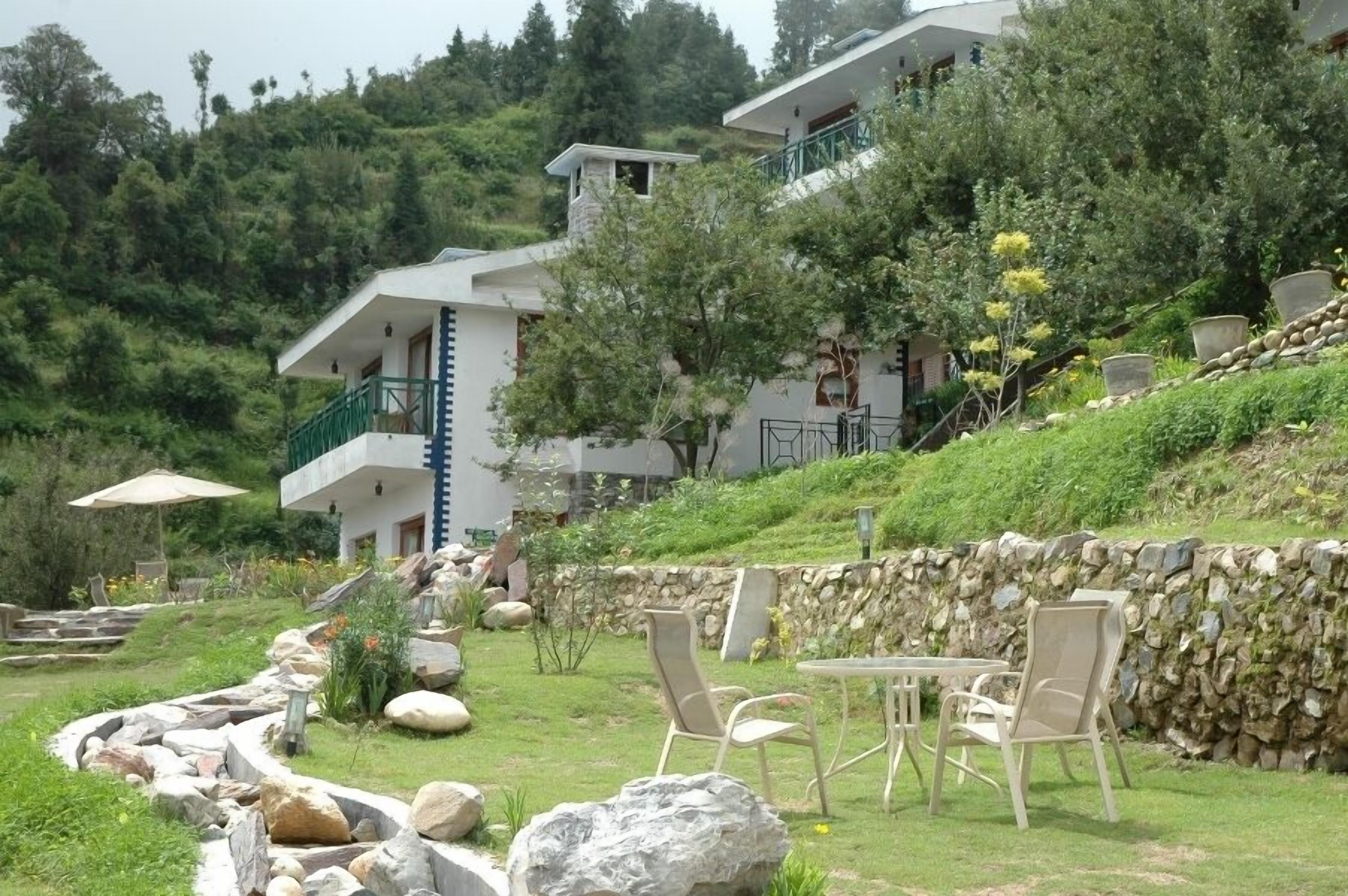 A hillside hotel with outdoor seating and a stone wall.