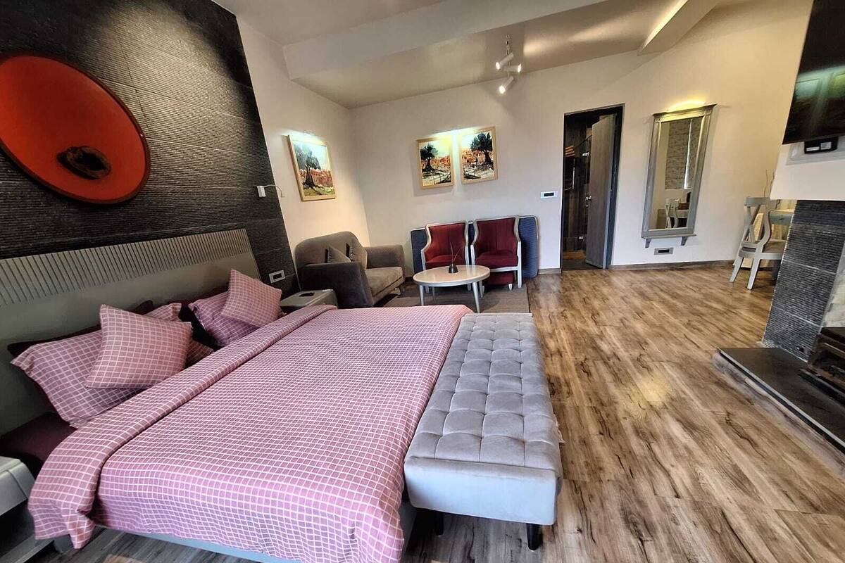 A modern bedroom with a large bed, a seating area with chairs, and artwork on the walls.