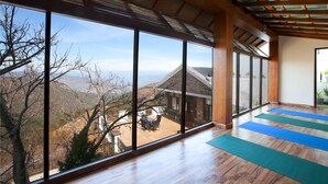 A spacious room with large windows offering a view of a mountainous landscape.