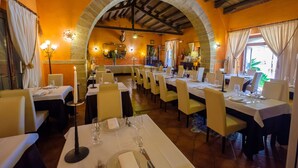 Un restaurante con varias mesas, sillas y un arco de piedra.