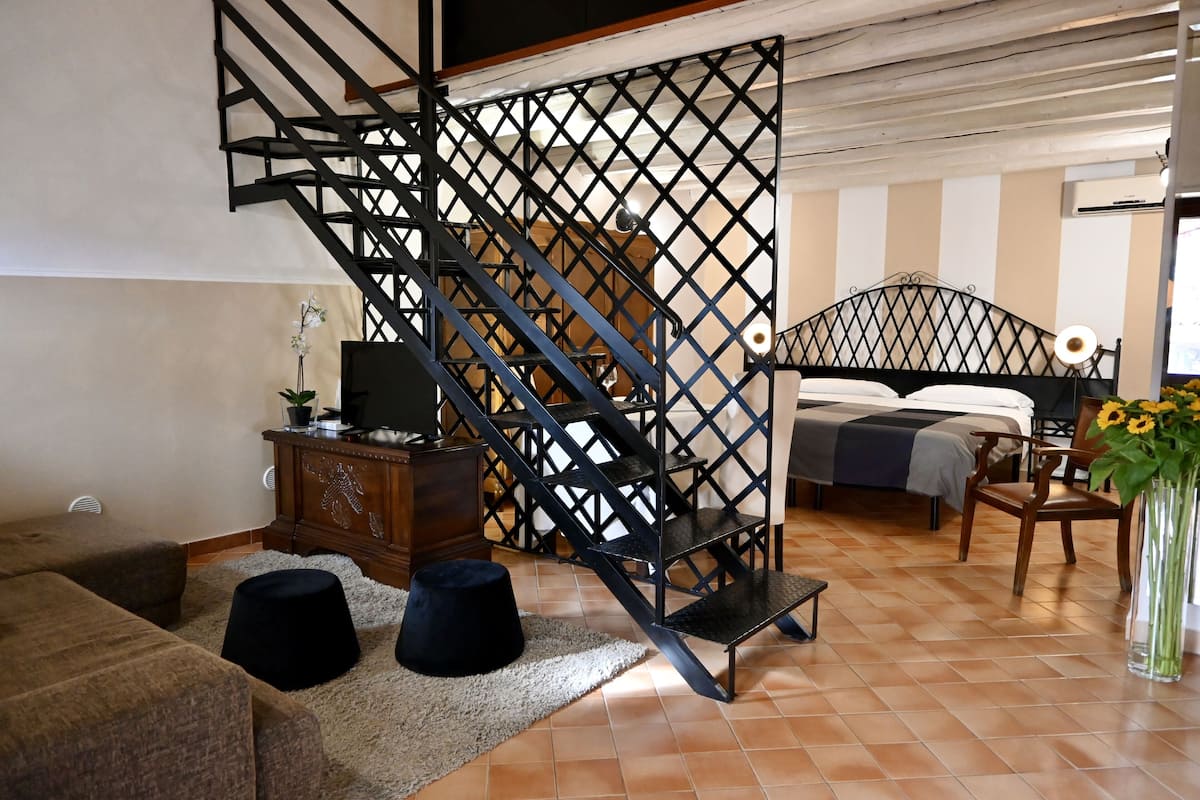 Ein modernes Wohnzimmer mit Treppe, einem Bett, einem Fernseher und einem Sofa.