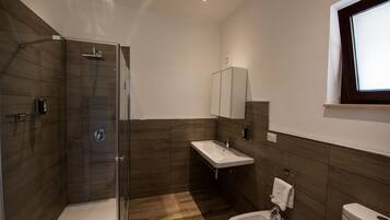Ein modernes Badezimmer mit einer Glasdusche, einem Waschbecken und einer Toilette.